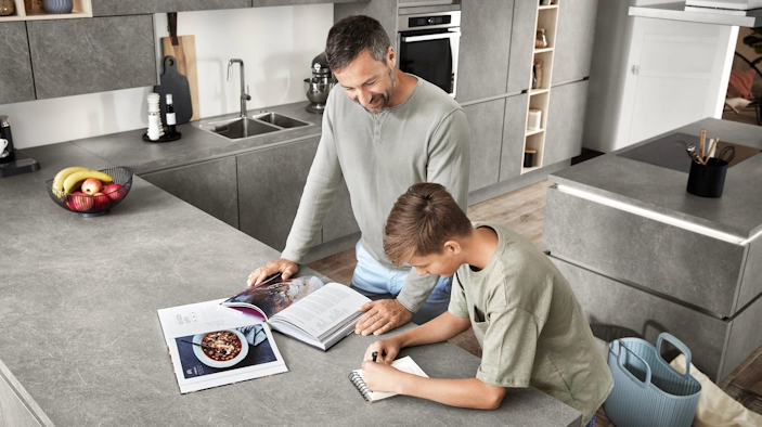 Vater plant das Mittagessen mit seinem Sohn in einer hellgrauen Küche. Vater plant das Mittagessen mit seinem Sohn in einer hellgrauen Küche.