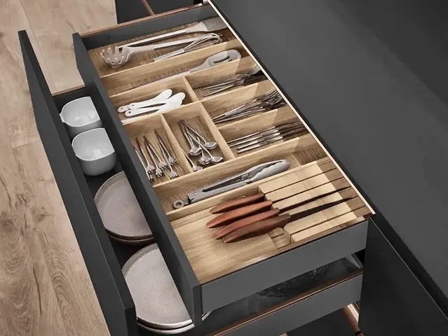 Eine Küchenschublade mit verschiedenen Utensilien und Tellern, die so angeordnet sind, dass sie bei der Essenszubereitung leicht zugänglich und verwendbar sind. Eine Küchenschublade mit verschiedenen Utensilien und Tellern, die so angeordnet sind, dass sie bei der Essenszubereitung leicht zugänglich und verwendbar sind.