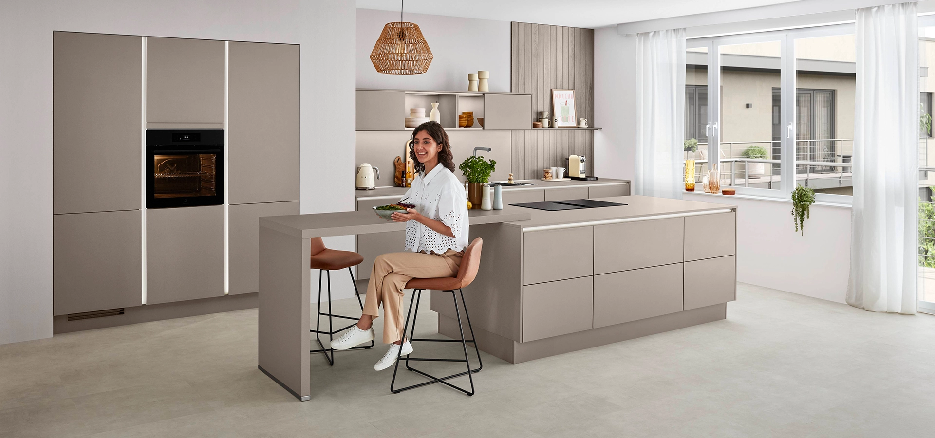 Junge Dame hält eine Salatschale in einer beigen grifflosen Küche. Junge Dame hält eine Salatschale in einer beigen grifflosen Küche.