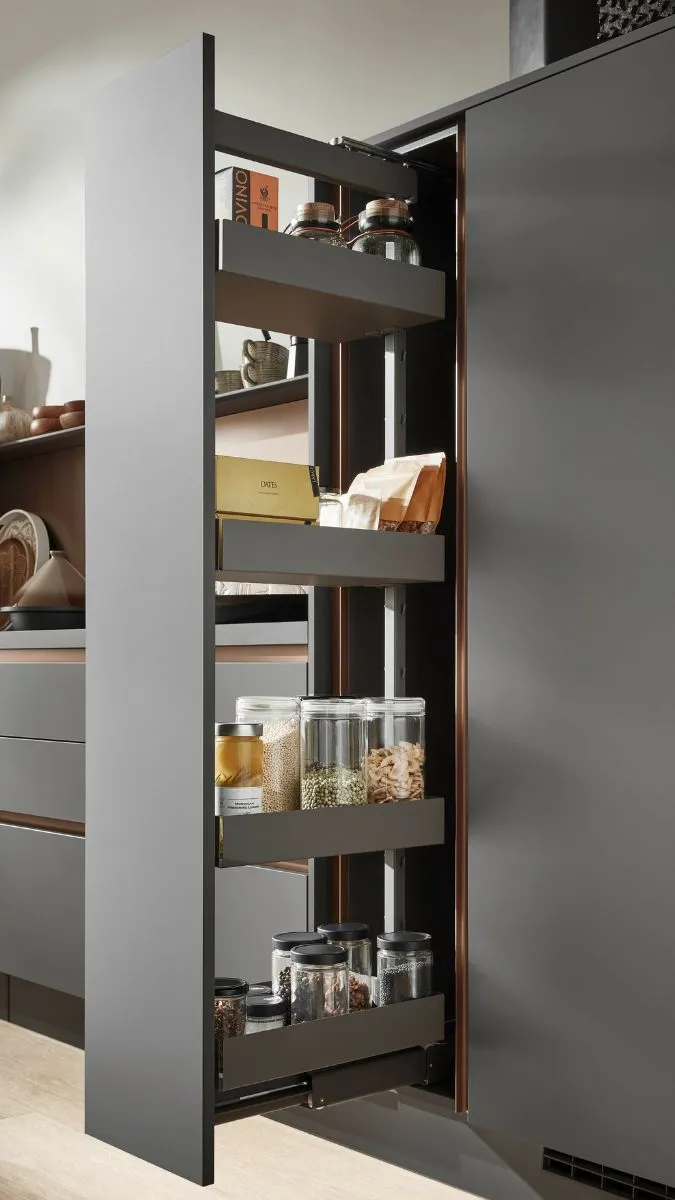 Ausgezogener, dunkler Küchen-Apothekerschrank mit Vorräten und kupferfarbenen Akzenten. Ausgezogener, dunkler Küchen-Apothekerschrank mit Vorräten und kupferfarbenen Akzenten.