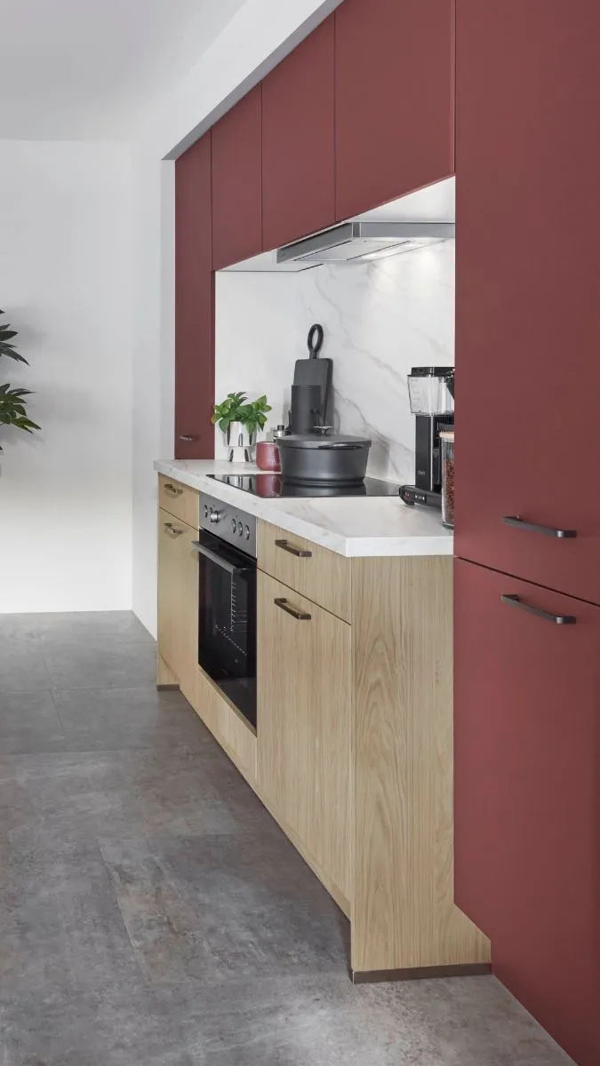 Küchenzeile mit rostroten und holzton Schränken, weißer Arbeitsplatte und Herd. Küchenzeile mit rostroten und holzton Schränken, weißer Arbeitsplatte und Herd.