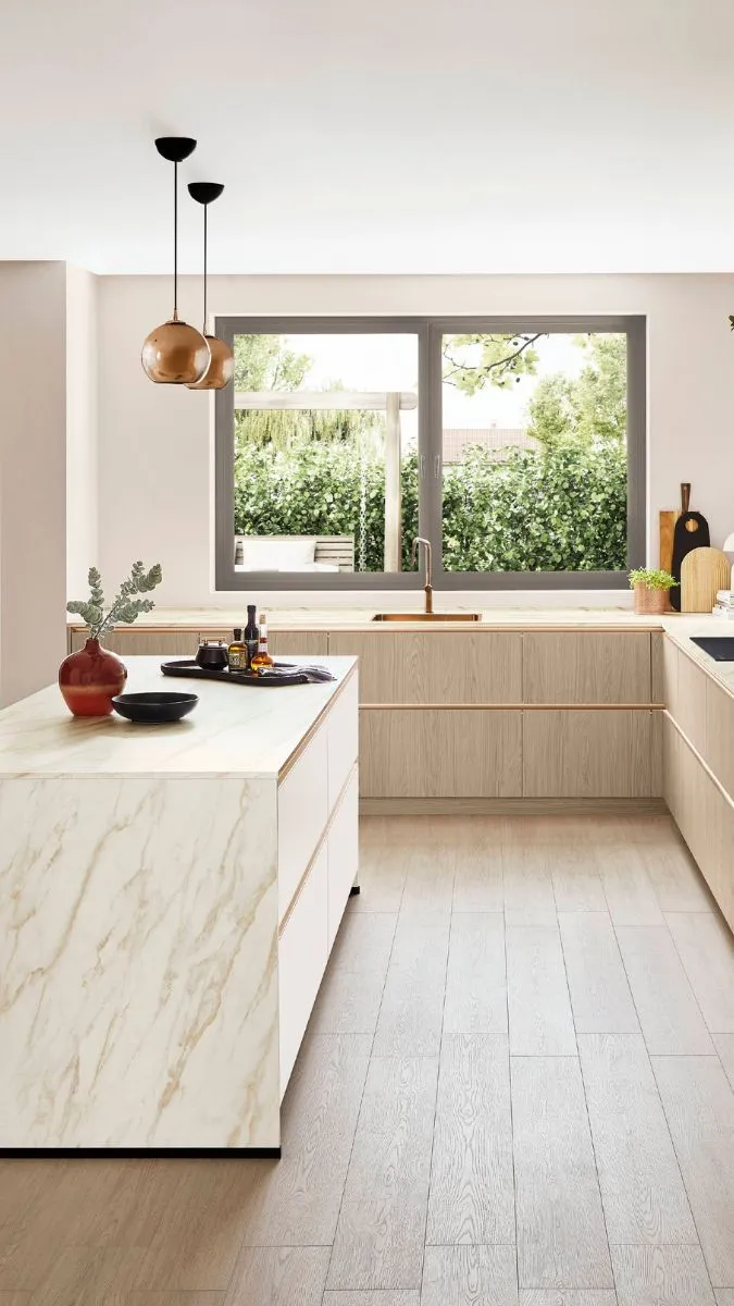 Helle Küche mit Holzfronten, einer freistehenden Kücheninsel mit einer Arbeitsplatte im Marmor-Look Helle Küche mit Holzfronten, einer freistehenden Kücheninsel mit einer Arbeitsplatte im Marmor-Look