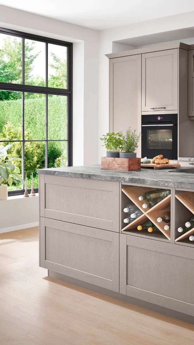 Küche mit schlichten hellgrauen Schränken, Arbeitsplatte in Steinoptik und großem, vertikalem Fenster. Küche mit schlichten hellgrauen Schränken, Arbeitsplatte in Steinoptik und großem, vertikalem Fenster.