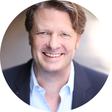 Rundes Porträtfoto von Dr. Stefan Wriggers. Blonde Haare, keine Brille, er lächelt. Er trägt ein hellblaues Hemd und ein dunkles Sakko.