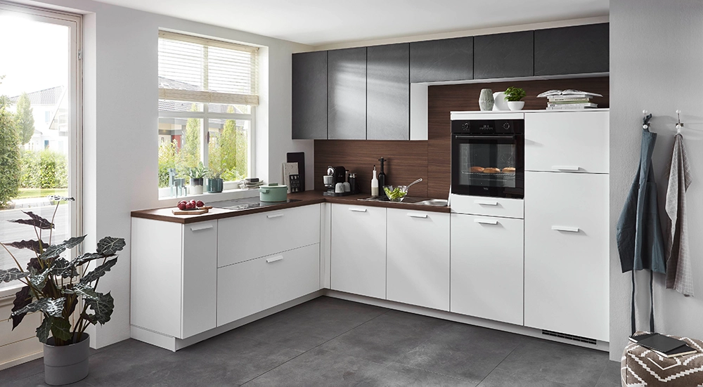 L-förmige Küche mit weißen Unterschränken, dunklen Oberschränken und Holzarbeitsplatte; integrierter Backofen, große Fenster und helle, freundliche Raumgestaltung. L-förmige Küche mit weißen Unterschränken, dunklen Oberschränken und Holzarbeitsplatte; integrierter Backofen, große Fenster und helle, freundliche Raumgestaltung.