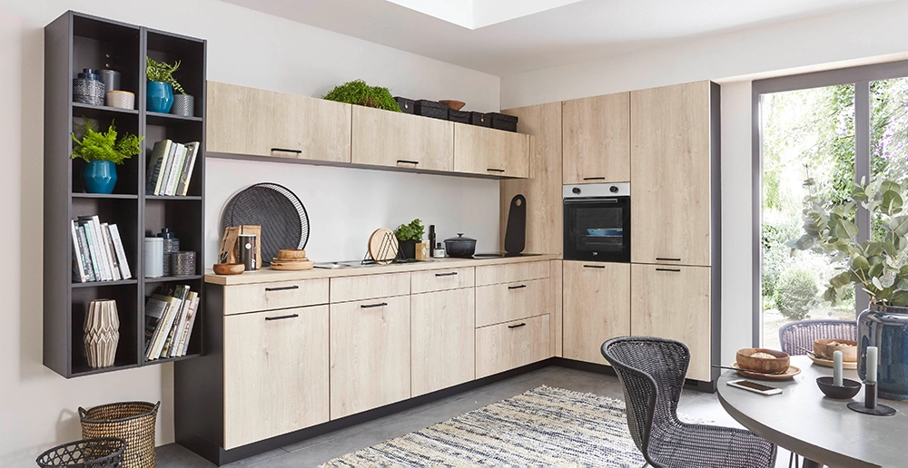 L-förmige Küche mit hellen Holzfronten, schwarzen Griffen, hochgebautem Backofen und offenen Regalen; daneben ein Essbereich vor einem großen Fenster. L-förmige Küche mit hellen Holzfronten, schwarzen Griffen, hochgebautem Backofen und offenen Regalen; daneben ein Essbereich vor einem großen Fenster.