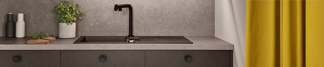 Ausschnitt einer einzeiligen Küche mit dunkler Front und Kopfgriffen. Spüle und Mischbatterie sind schwarz. Ausschnitt einer einzeiligen Küche mit dunkler Front und Kopfgriffen. Spüle und Mischbatterie sind schwarz.