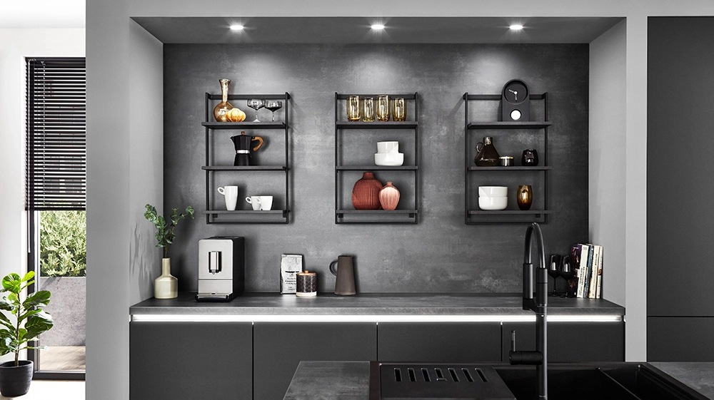 Ausschnitt einer Küche mit grauen Fronten betongrauer Nischenwandverkleidung. Auf der Nischenwandverkleidung sind Regale angebracht. Ausschnitt einer Küche mit grauen Fronten betongrauer Nischenwandverkleidung. Auf der Nischenwandverkleidung sind Regale angebracht.