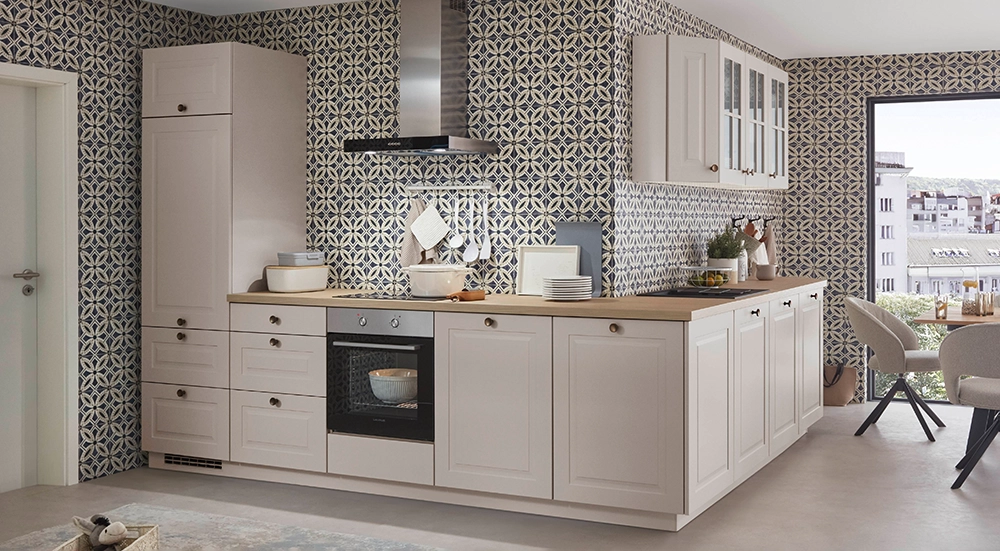 Helle Küche im Landhausstil mit cremefarbenen Fronten, Holzarbeitsplatte, Edelstahl-Dunstabzug und gemusterten Wandfliesen; rechts ein Essbereich mit großem Fenster und Stadtblick. Helle Küche im Landhausstil mit cremefarbenen Fronten, Holzarbeitsplatte, Edelstahl-Dunstabzug und gemusterten Wandfliesen; rechts ein Essbereich mit großem Fenster und Stadtblick.