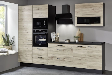 Moderne Küchenzeile in heller Holzoptik mit schwarzen Griffen, integrierten Backöfen, schwarzer Dunstabzugshaube und dunkler Arbeitsplatte vor grauer Wand. Moderne Küchenzeile in heller Holzoptik mit schwarzen Griffen, integrierten Backöfen, schwarzer Dunstabzugshaube und dunkler Arbeitsplatte vor grauer Wand.
