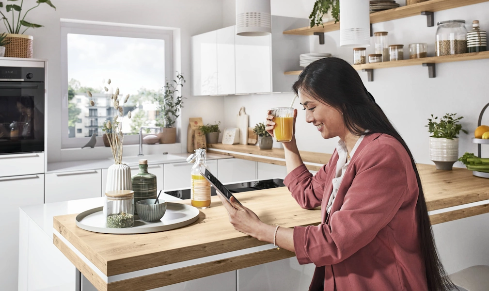 Frau an weißer Kücheninsel mit einem Tablet Frau an weißer Kücheninsel mit einem Tablet