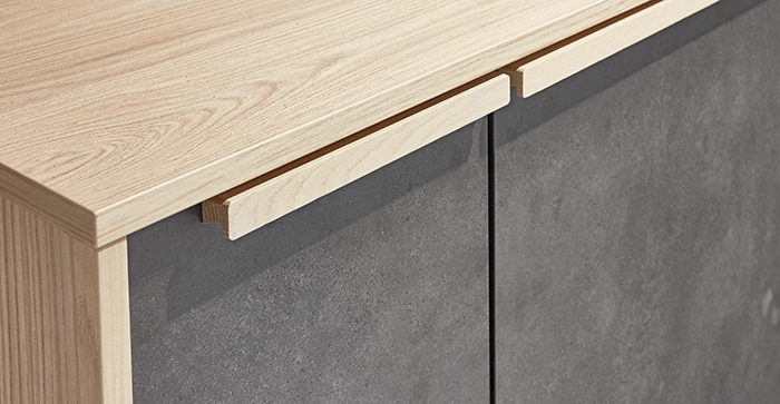 Nahaufnahme einer Küchenfront mit grauen Türen und einer hellen Holzarbeitsplatte samt passender Holzgriffleiste. Nahaufnahme einer Küchenfront mit grauen Türen und einer hellen Holzarbeitsplatte samt passender Holzgriffleiste.
