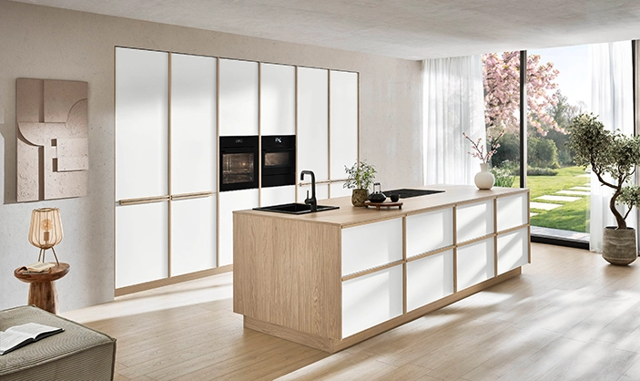 Küche im Japandi-Stil mit sehr angenehmem Tageslichteinfall. Die Fronten sind cremeweiß, Griffe und Wangen haben einen Holzton. Küche im Japandi-Stil mit sehr angenehmem Tageslichteinfall. Die Fronten sind cremeweiß, Griffe und Wangen haben einen Holzton.