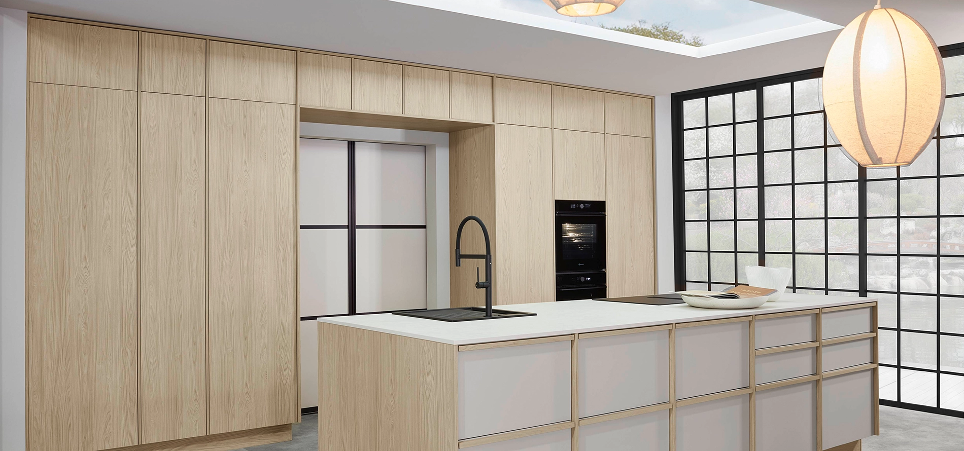 Moderne Küche in heller Holzoptik mit Kücheninsel, schwarzem Wasserhahn, integriertem Backofen und großer Fensterfront. Moderne Küche in heller Holzoptik mit Kücheninsel, schwarzem Wasserhahn, integriertem Backofen und großer Fensterfront.