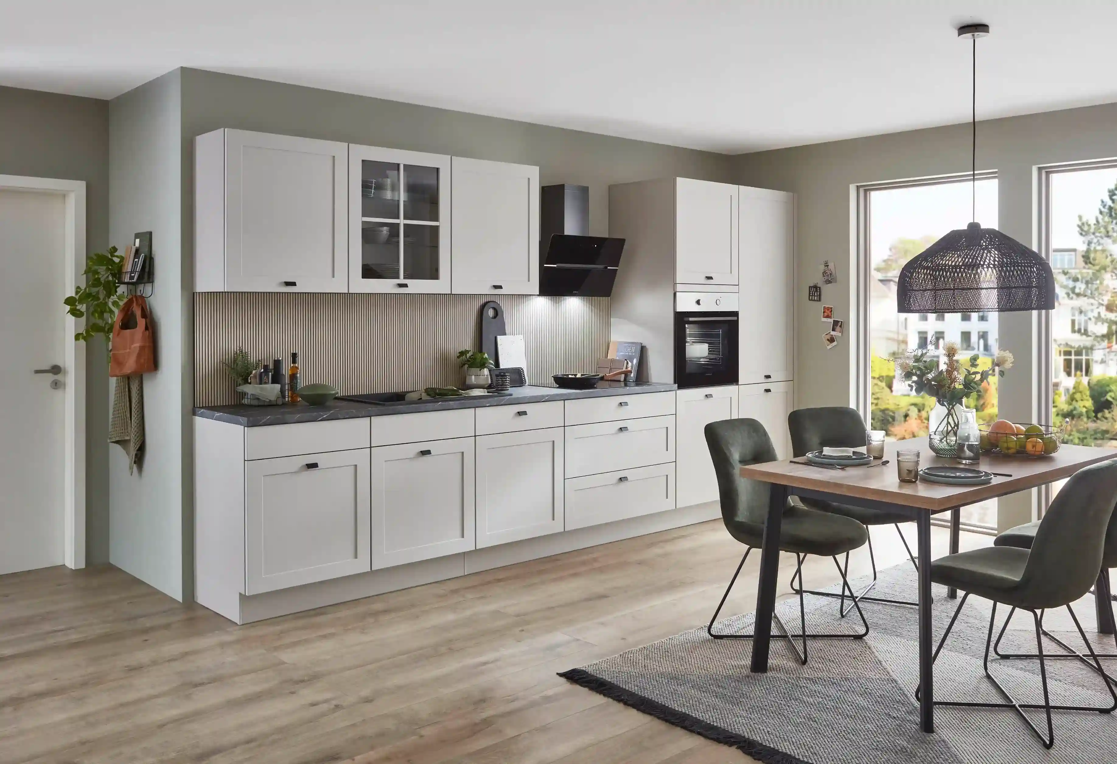 Inselküche mit hellgrauen Landhausfronten, teilweise mit Glasfronten, und liebevoll gestalteten Details im klassischen Küchenstil Inselküche mit hellgrauen Landhausfronten, teilweise mit Glasfronten, und liebevoll gestalteten Details im klassischen Küchenstil