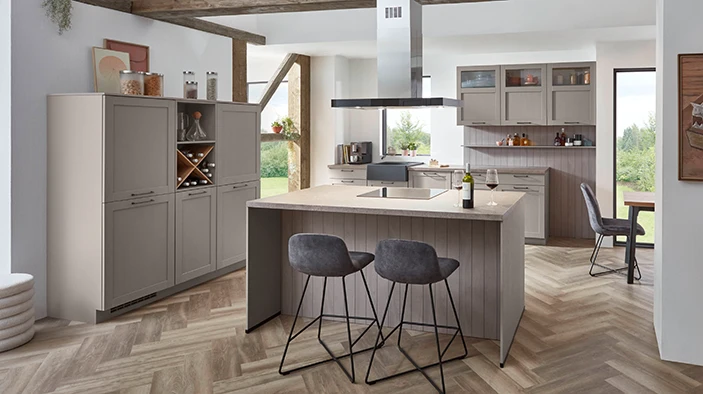 Eine Landhausküche in einer hellen Kaffeefarbe. Sie besteht aus einer Zeile mit Highboards, einer Ziele mit Unter- und Wandschränken, sowie einer Kochinsel. Eine Landhausküche in einer hellen Kaffeefarbe. Sie besteht aus einer Zeile mit Highboards, einer Ziele mit Unter- und Wandschränken, sowie einer Kochinsel.