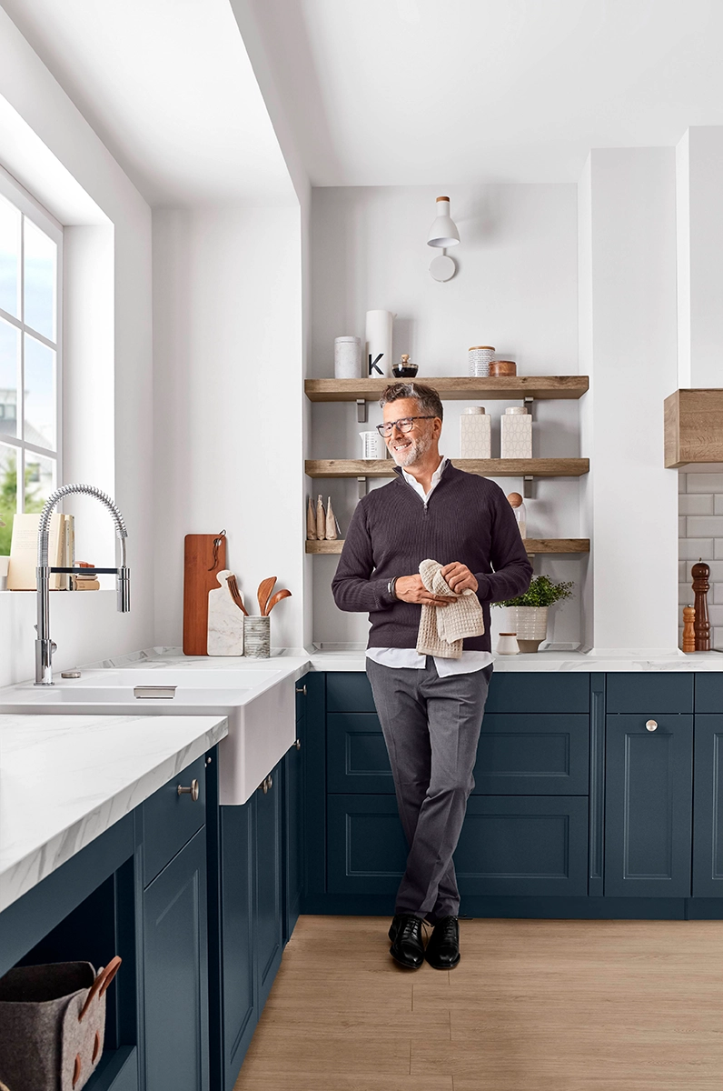 Erwachsener Mann schaut zufrieden in seiner neuen Küche aus dem Fenster.