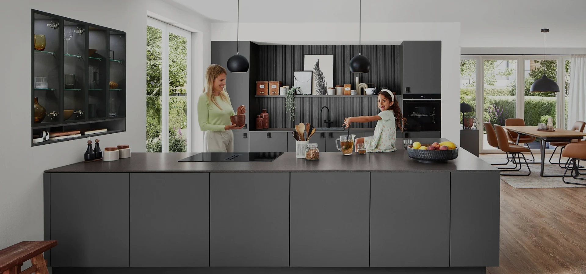 Mutter und Tochter bereiten Speisen in einer grauen, grifflosen Küche vor. Mutter und Tochter bereiten Speisen in einer grauen, grifflosen Küche vor.