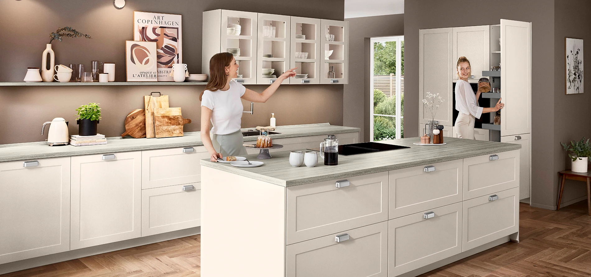 Zwei Frauen sind in einer weißen Küche mit Rahmenfront und bereiten eine Mahlzeit vor. Zwei Frauen sind in einer weißen Küche mit Rahmenfront und bereiten eine Mahlzeit vor.