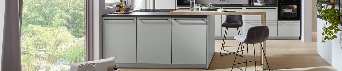 Helle moderne Insel-Küche mit Theke, grauen Fronten und schwarzer Arbeitsplatte in offenem Wohnraum. Helle moderne Insel-Küche mit Theke, grauen Fronten und schwarzer Arbeitsplatte in offenem Wohnraum.