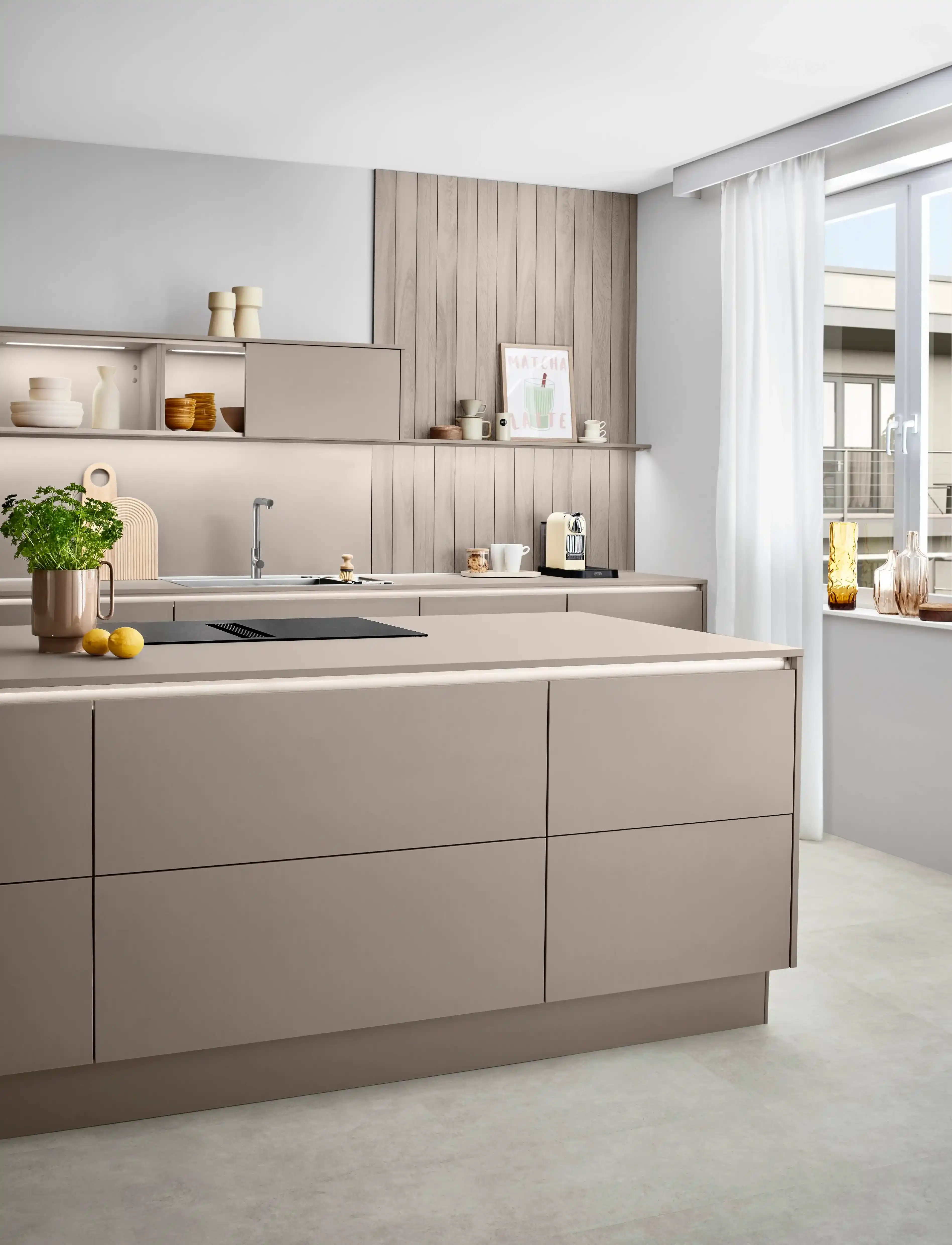 Moderne Küche mit Kochinsel mit matten Beigefronten und beleuchteten Griffleisten. Moderne Küche mit Kochinsel mit matten Beigefronten und beleuchteten Griffleisten.