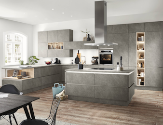 Eine große graue Inselküche mit einzelnen Holzelementen in einem hellen Raum. Eine große graue Inselküche mit einzelnen Holzelementen in einem hellen Raum.
