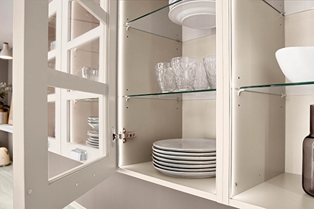 Küchenplanung mit weißen Wandschränken mit gerahmter Sprossenfront. Ein Wandschrank ist geöffnet, Geschirr ist im Wandschrank. Küchenplanung mit weißen Wandschränken mit gerahmter Sprossenfront. Ein Wandschrank ist geöffnet, Geschirr ist im Wandschrank.