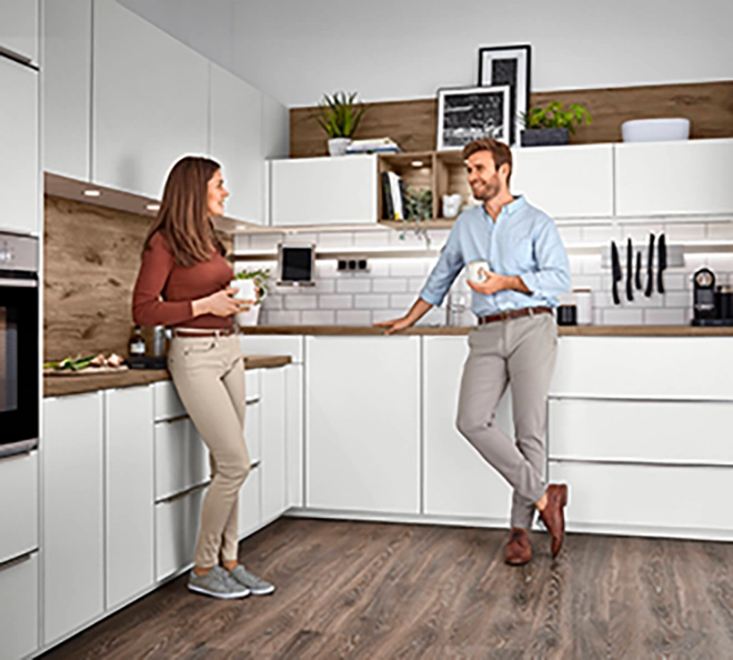 Weiße Eckküche mit zwei Personen beim Kaffee trinken und Unterhalten als Beispiel für funktionale Küchenformen im Alltag Weiße Eckküche mit zwei Personen beim Kaffee trinken und Unterhalten als Beispiel für funktionale Küchenformen im Alltag