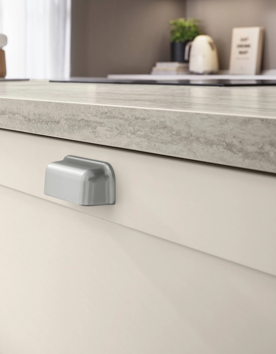 Nahaufnahme der Arbeitsplatte in Betonoptik mit sichtbarem Metallgriff einer hellen Landhausküche. Nahaufnahme der Arbeitsplatte in Betonoptik mit sichtbarem Metallgriff einer hellen Landhausküche.