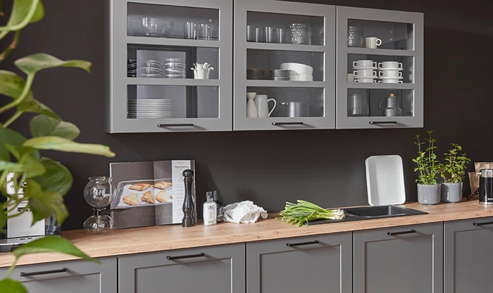 Ausschnitt einer mediterranen Küche mit versteckten Elektrogeräten. Die Fronten sind mittelgrau und die Arbeitsplatte hat einen Holzton. Ausschnitt einer mediterranen Küche mit versteckten Elektrogeräten. Die Fronten sind mittelgrau und die Arbeitsplatte hat einen Holzton.