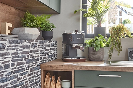Ausschnitt einer Küche im modern natural Stil mit Grünpflanzen und Kräutern. Links eine Wand im Natursteinstil. Zwischen den Pflanzen steht eine Kaffeemaschine. Ausschnitt einer Küche im modern natural Stil mit Grünpflanzen und Kräutern. Links eine Wand im Natursteinstil. Zwischen den Pflanzen steht eine Kaffeemaschine.
