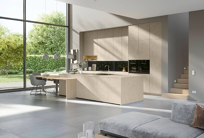 Blick auf eine Wohnküche im modern natural Trend. Sandfarbene matte Fronten. Die Fenster sind bodentief, wir blicken auf Wiese und Bäume. Blick auf eine Wohnküche im modern natural Trend. Sandfarbene matte Fronten. Die Fenster sind bodentief, wir blicken auf Wiese und Bäume.