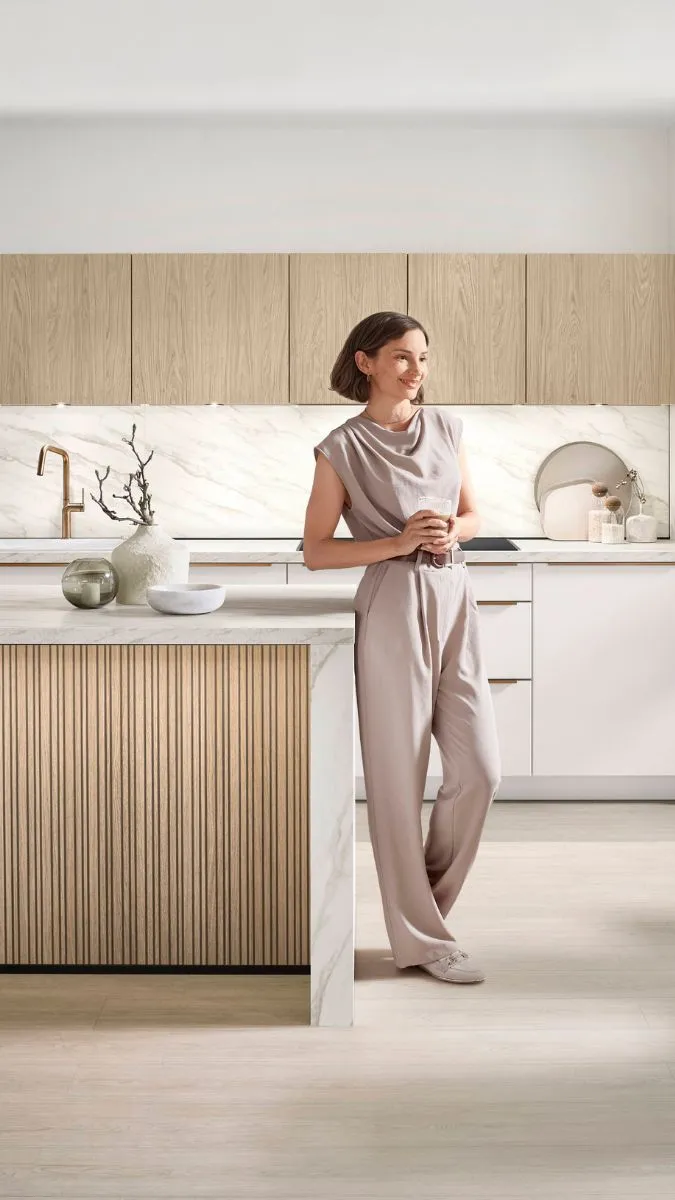 Helle moderne Küche mit Holz- und Marmorakzenten und einer Person an der Kochinsel. Helle moderne Küche mit Holz- und Marmorakzenten und einer Person an der Kochinsel.