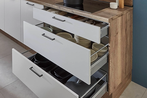 Geöffnete Auszüge und Schublade in einer Pantryküche. Weiße Front mit Arbeitsplatte in dunklem Holzton. Geöffnete Auszüge und Schublade in einer Pantryküche. Weiße Front mit Arbeitsplatte in dunklem Holzton.