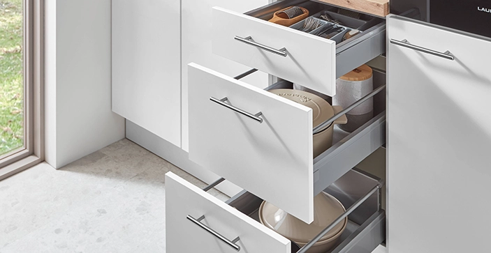 Weiße, geöffnete Schublade und Auszüge in einer Pantryküche. Die Griffe sind edelstahl-grau Weiße, geöffnete Schublade und Auszüge in einer Pantryküche. Die Griffe sind edelstahl-grau