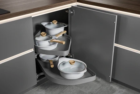 Geöffneter Kücheneckschrank mit schwenkbarem Auszugssystem, mehrere Töpfe und Pfannen übersichtlich verstaut, praktische Lösung für Stauraum in der Eckküche. Geöffneter Kücheneckschrank mit schwenkbarem Auszugssystem, mehrere Töpfe und Pfannen übersichtlich verstaut, praktische Lösung für Stauraum in der Eckküche.