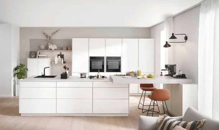 Weiße, moderne Küche mit großer Insel, weißen Fronten und integriertem Sitzbereich Weiße, moderne Küche mit großer Insel, weißen Fronten und integriertem Sitzbereich