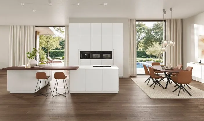 Moderne offene Wohnküche mit weißen Küchenfronten, Kochinsel und Holzakzenten, kombiniert mit braunen Stühlen und dunklem Holzboden, mit Blick in den Garten. Moderne offene Wohnküche mit weißen Küchenfronten, Kochinsel und Holzakzenten, kombiniert mit braunen Stühlen und dunklem Holzboden, mit Blick in den Garten.