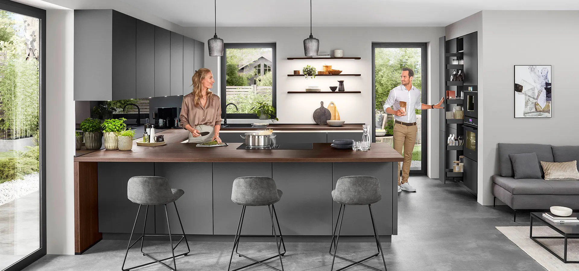 Moderne offene Küche mit Kochinsel, hellen Fenstern und zwei Personen im Raum. Moderne offene Küche mit Kochinsel, hellen Fenstern und zwei Personen im Raum.