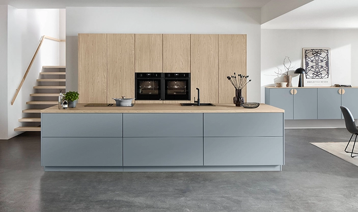 Inselküche mit himmelblauen Mattfronten, hölzerner Arbeitsplatte und Holzschränken als zweifarbige Küche Inselküche mit himmelblauen Mattfronten, hölzerner Arbeitsplatte und Holzschränken als zweifarbige Küche