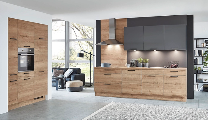 Offene zweizeilige Küche mit Fronten in Holzton. Dunkelgraue Wandschränke und schwarze Griffe. Offene zweizeilige Küche mit Fronten in Holzton. Dunkelgraue Wandschränke und schwarze Griffe.